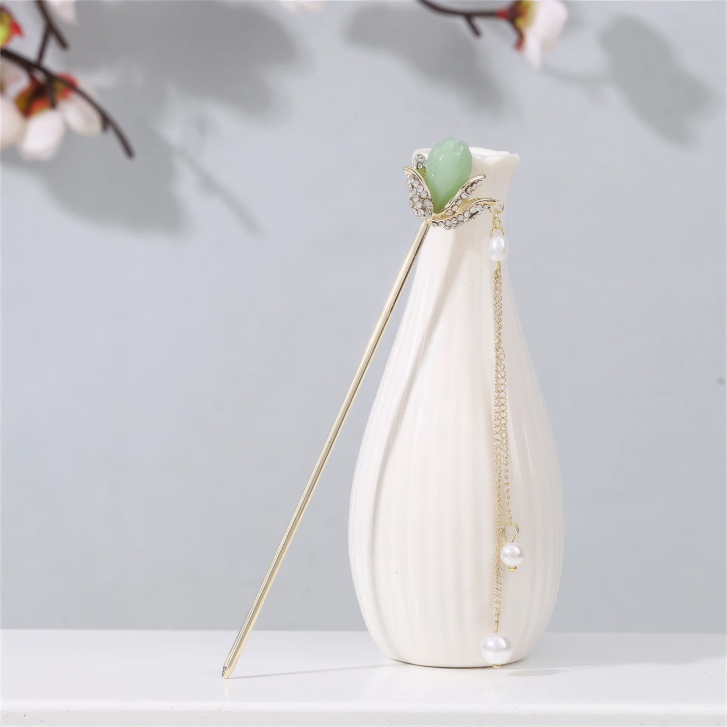 Jianjianjiao hairpin 3, gold rod with pearl and jade, placed on white vase against light gray background with plum blossoms