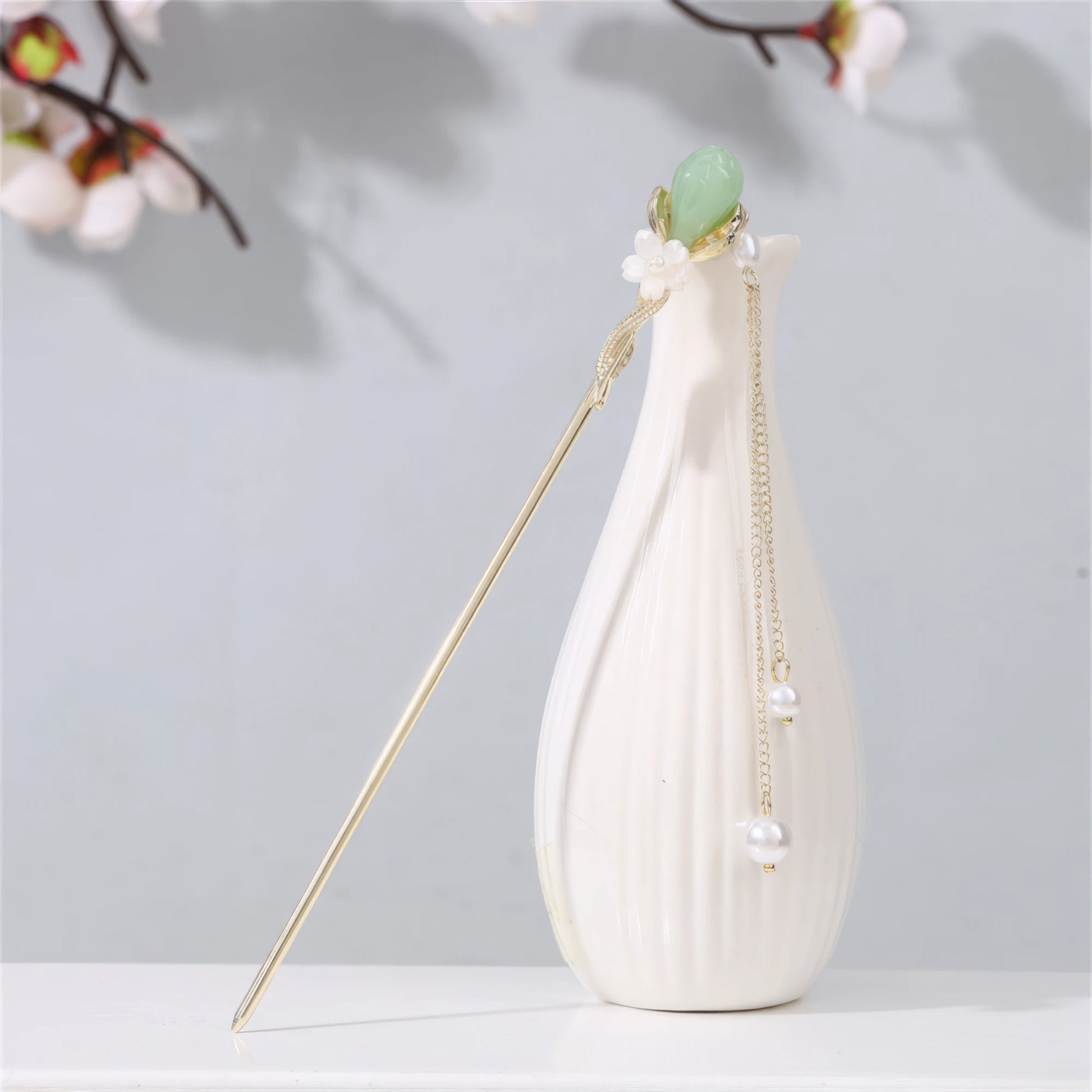 Jianjianjiao hairpin 4, gold rod with pearl and jade decoration, in white vase against light gray background with plum blossoms