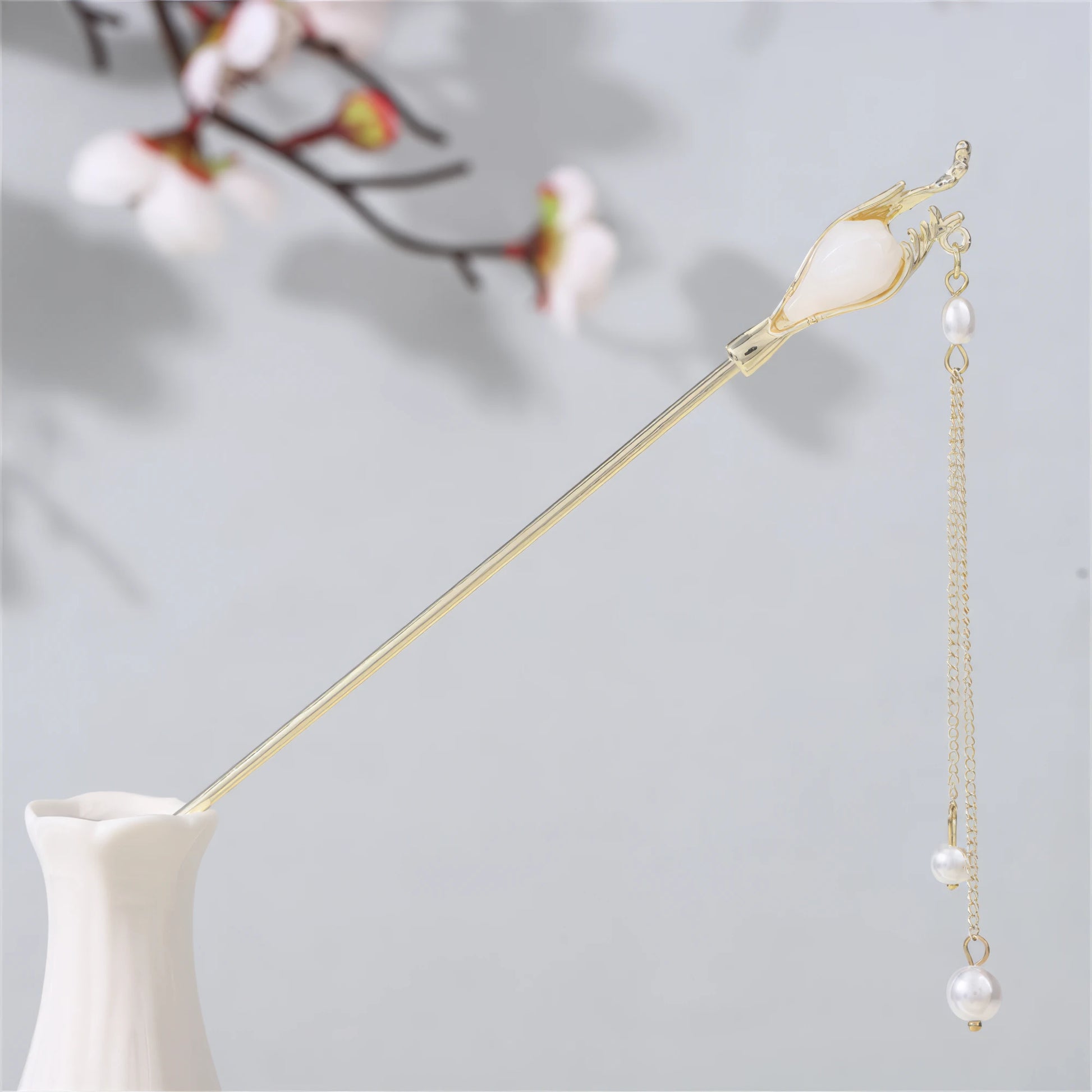 Jianjianjiao hairpin 5, gold rod with pearl tassel, in white vase against light gray background with plum blossoms