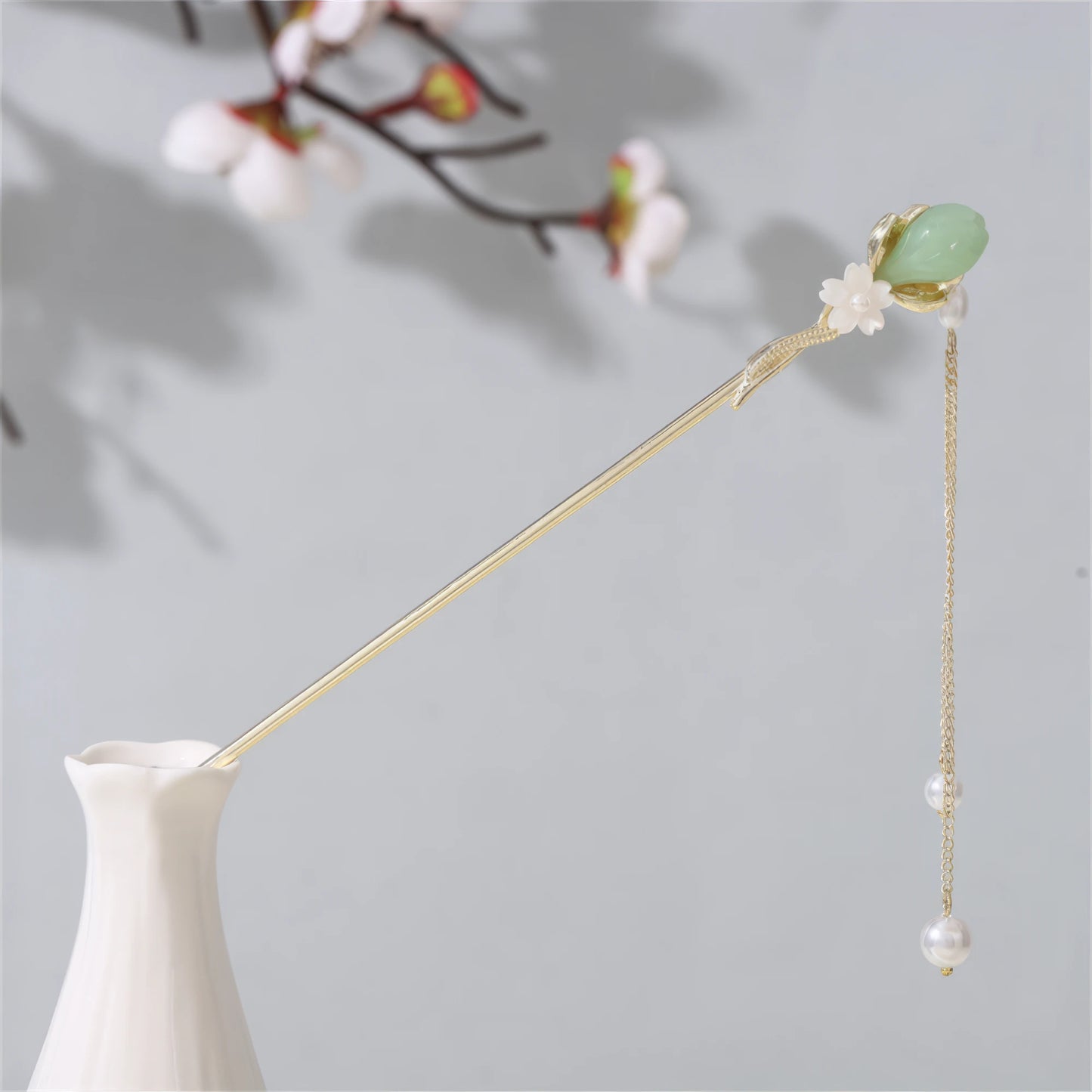 Jianjianjiao hairpin 7, gold rod with pearl, jade and flower, in white vase against light gray background with plum blossoms
