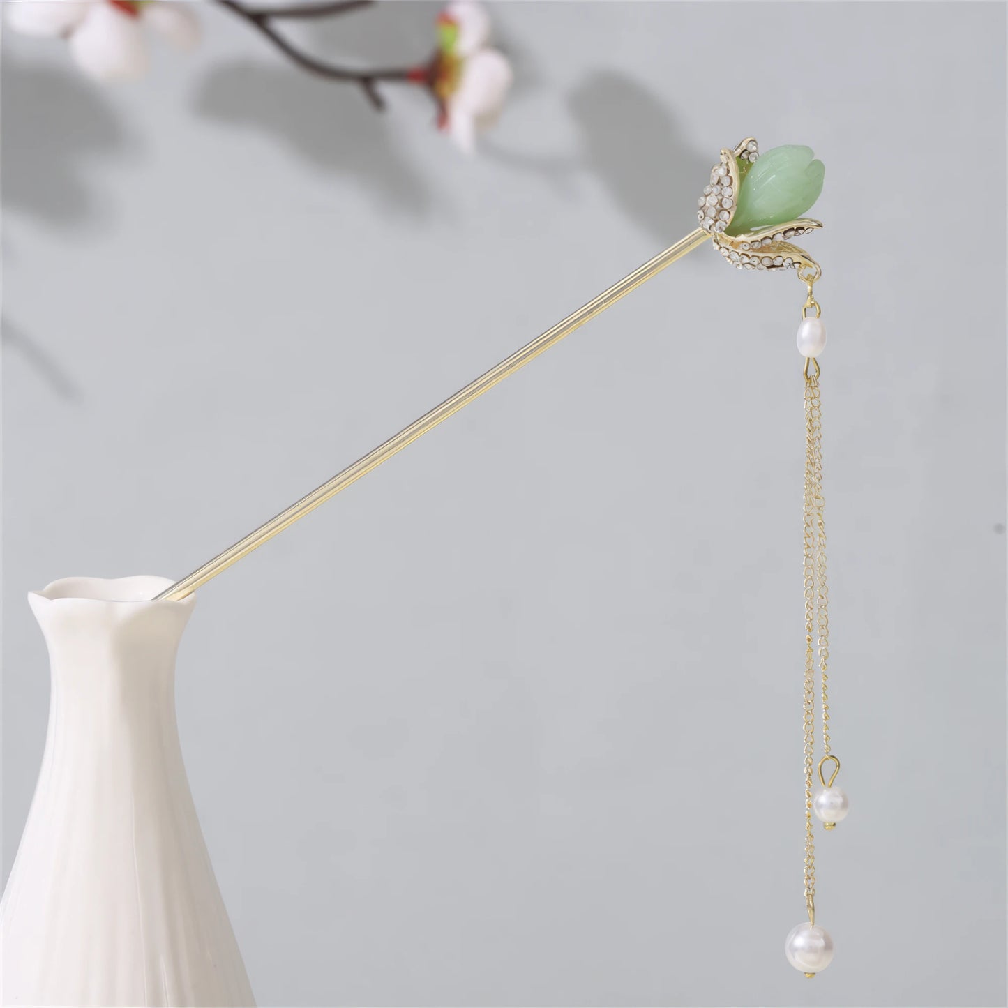 Jianjianjiao hairpin 8, gold rod with pearl, jade and tassel, in white vase against light gray background with plum blossoms