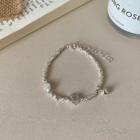 Kitten eating fish silver bracelet, displayed on light background with book and candle