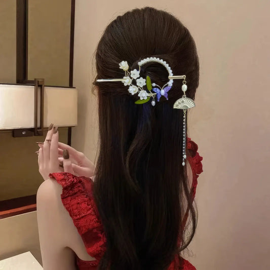Woman wearing a lily - of - the - valley tassel hairpin, back view, red top
