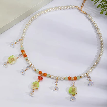 Lotus leaf and pumpkin necklace with pearls and colorful beads, displayed on light surface