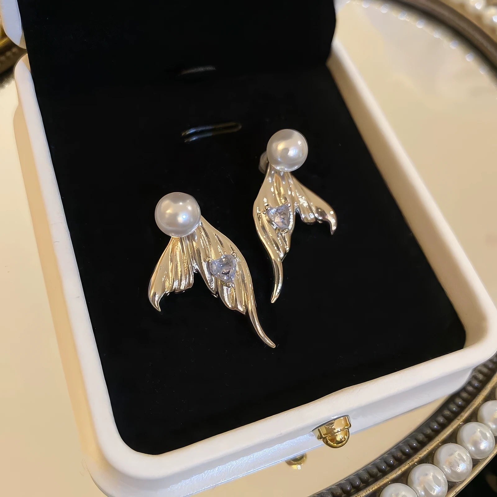 Gold mermaid tail heart diamond pearl earrings in jewelry box, showcasing elegance
