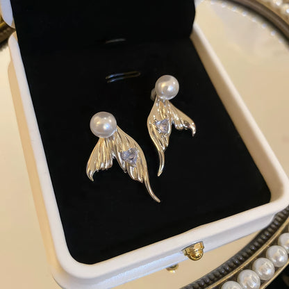 Gold mermaid tail heart diamond pearl earrings in jewelry box, showcasing elegance