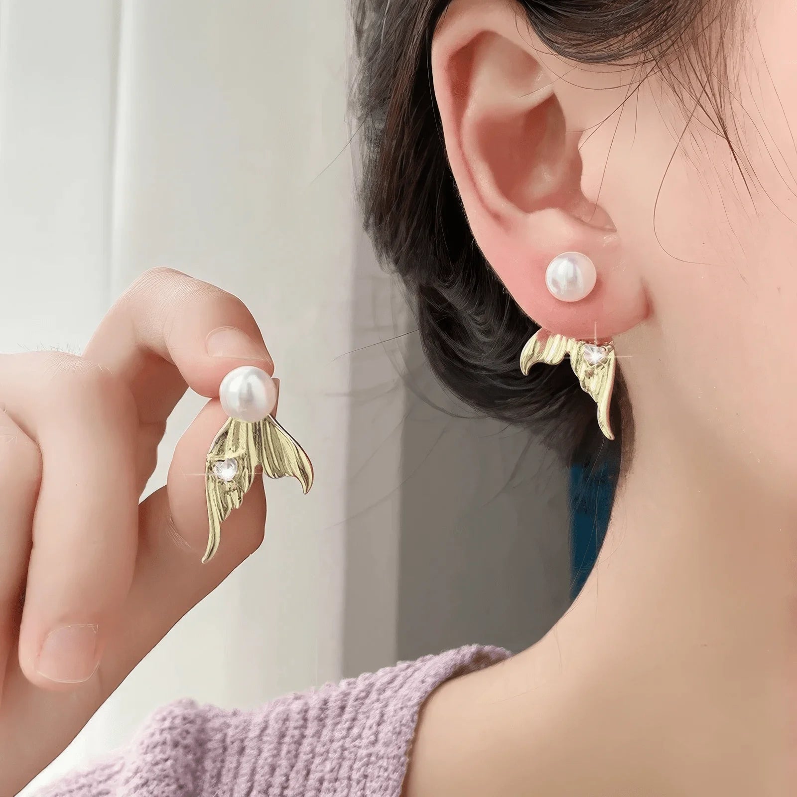 Gold mermaid tail heart diamond pearl earrings worn on ear, showcasing craftsmanship