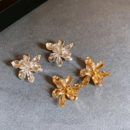 Mixed metal flower ear clips (silver and gold) displayed on a gray surface