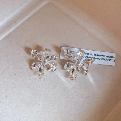 Silver metal flower ear clips isolated on a light surface with a card