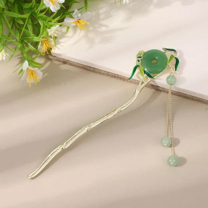 Moyunxuan hairpin, silver with green bead and tassel, on beige background with greenery