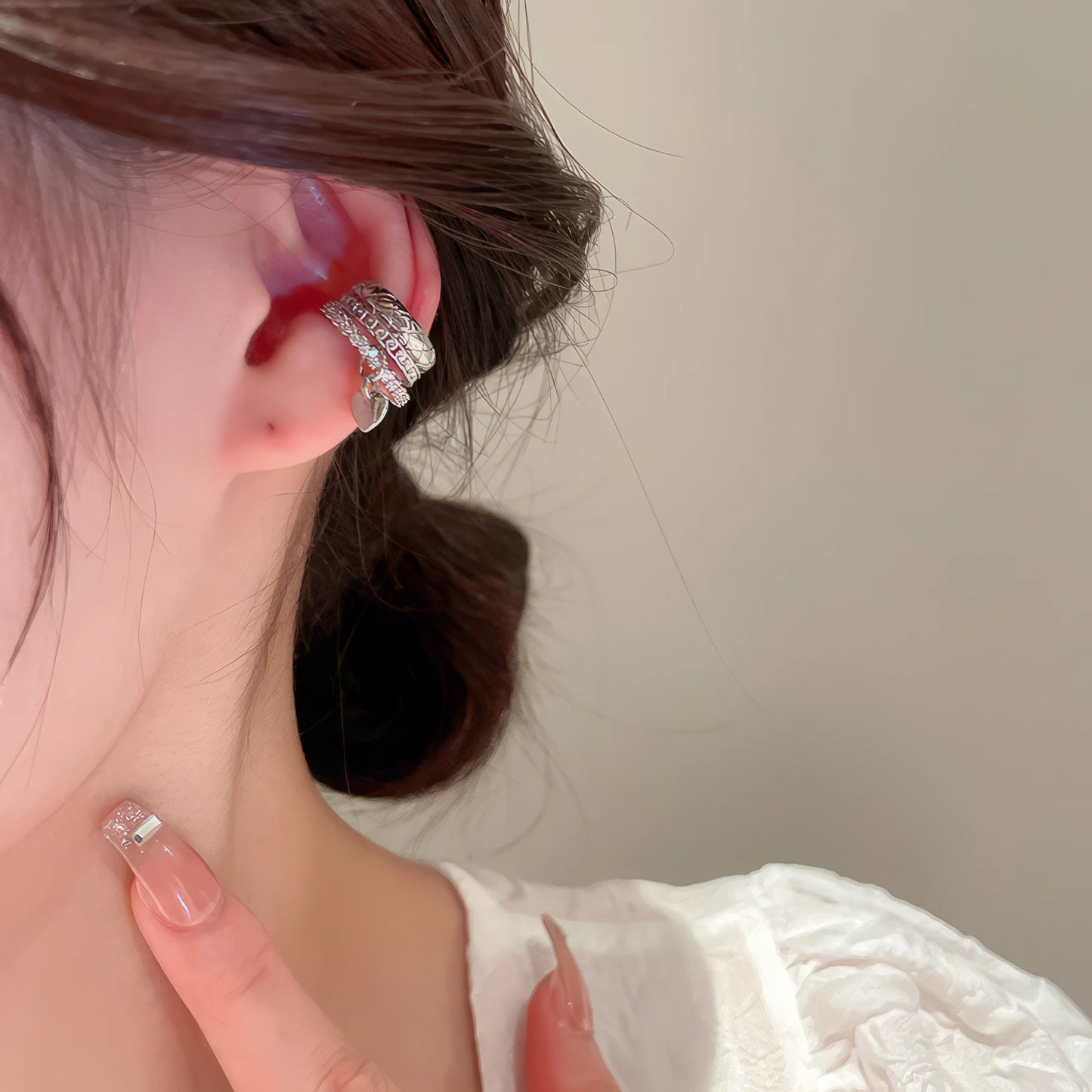 Multi - layer butterfly ear cuff on ear, with white clothing backdrop