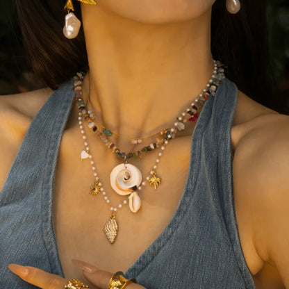 Natural shell beaded pendant necklace worn, highlighting details with hand gesture
