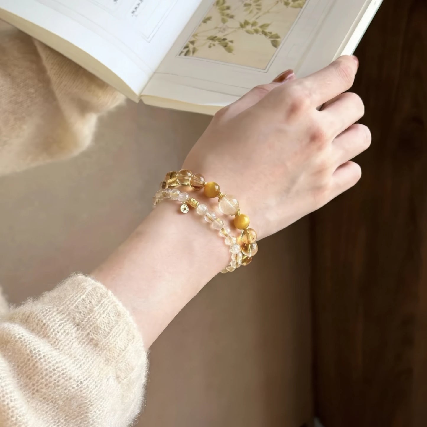 Natural stone citrine rutilated quartz bracelet worn on wrist while reading, highlighting elegance
