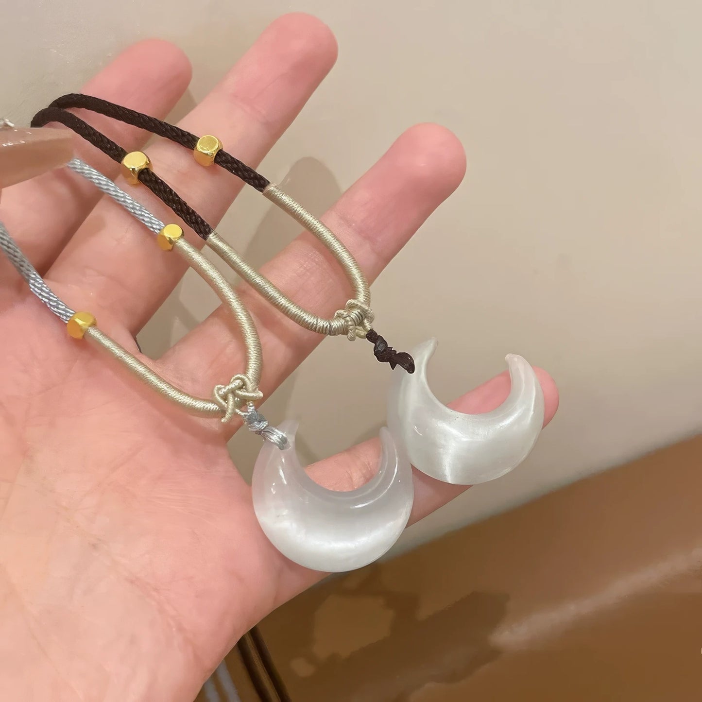 Hand holding new Chinese style cat's eye moon pendants, highlighting details