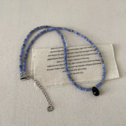 Blue new Chinese style handmade necklace, isolated on a textured background, showcasing a black bead pendant