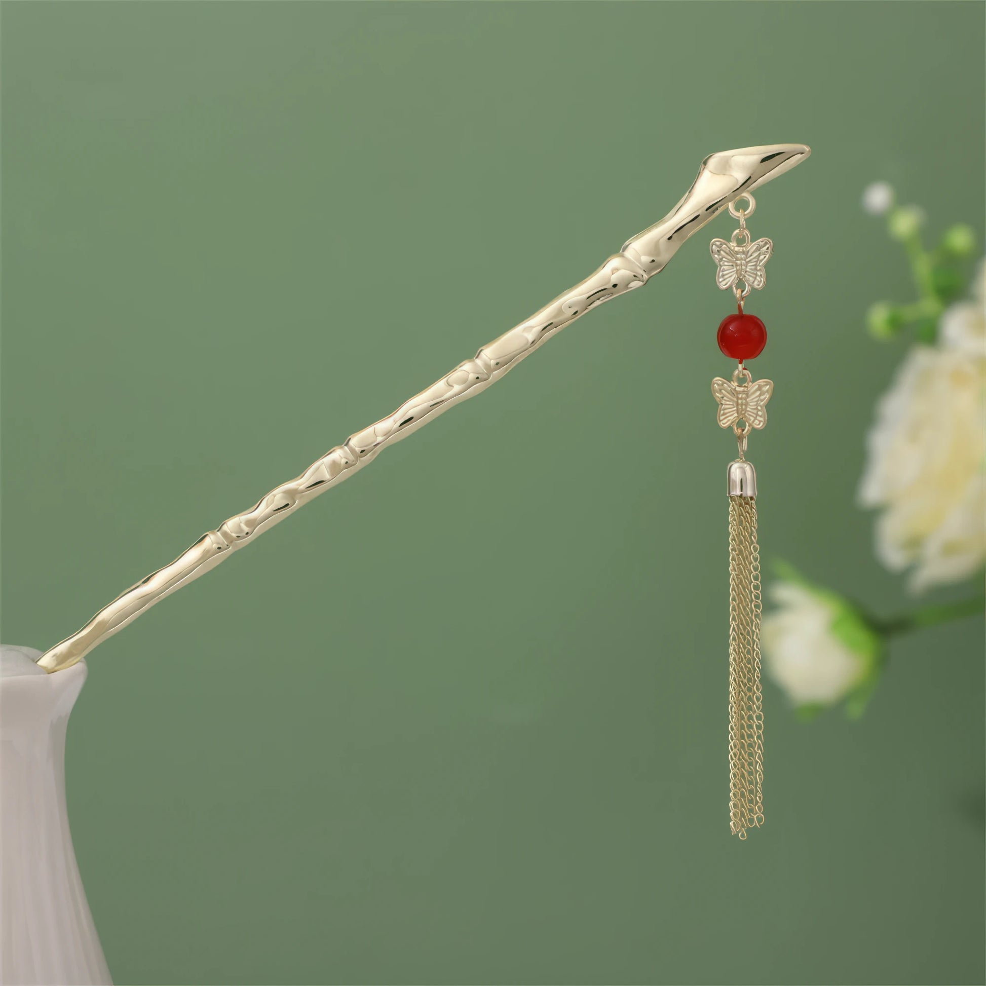 Nianchunxian hairpin featuring red bead and gold tassel, gold rod in white vase on green background