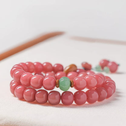 Double - strand peach pink white jade bodhi bracelet with green accent beads, displayed on white surface
