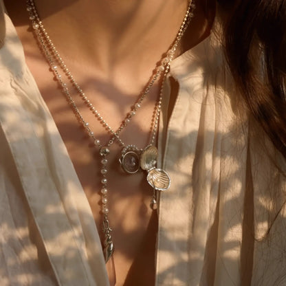 Layered pearl shell pendant necklaces worn, showcasing a stacked look