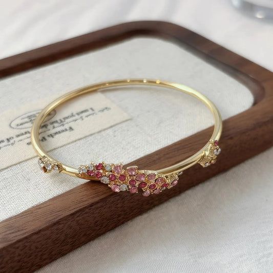 Pink flower wrapped bangle placed on a wooden tray with a card