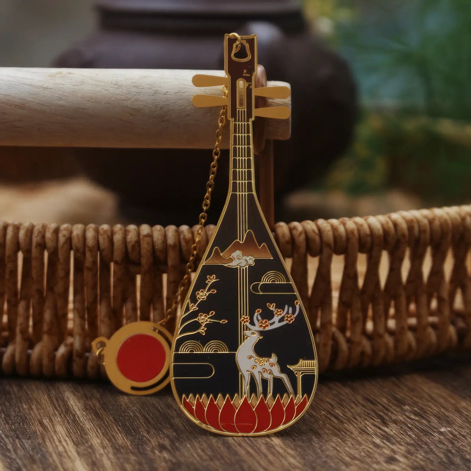 Pipa - shaped bookmark adorned with a black color and deer motif, having a small hanging chain, displayed on a woven basket backdrop.