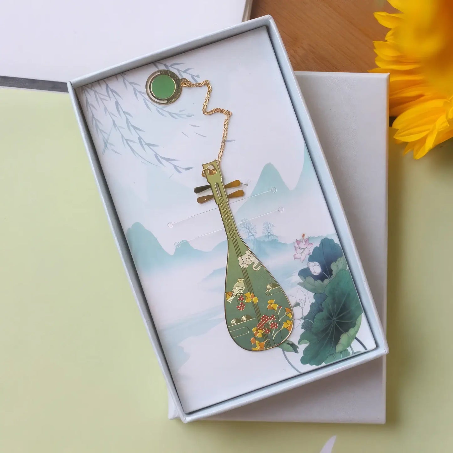 Pipa - shaped bookmark with vibrant colorful patterns, displayed in a white - bordered box with a landscape print, attached with a pendant chain.
