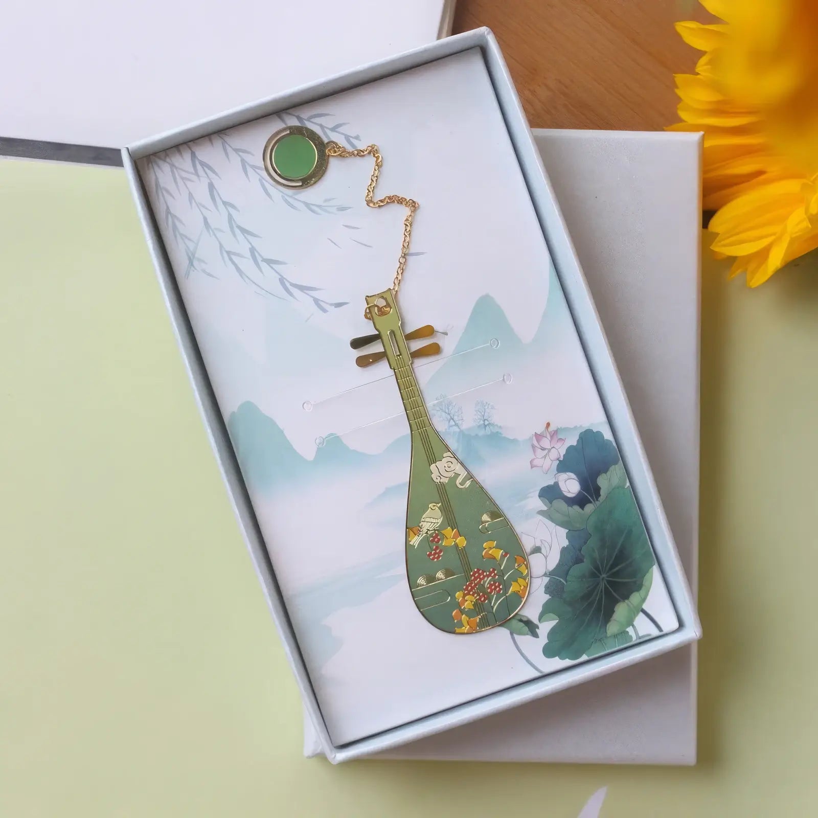 Pipa - shaped bookmark with vibrant colorful patterns, displayed in a white - bordered box with a landscape print, attached with a pendant chain.