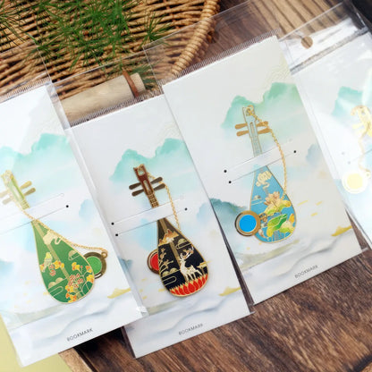 Set of pipa - shaped bookmarks, each in individual packages with scenic prints, featuring pendant chains, displayed on a wooden surface.