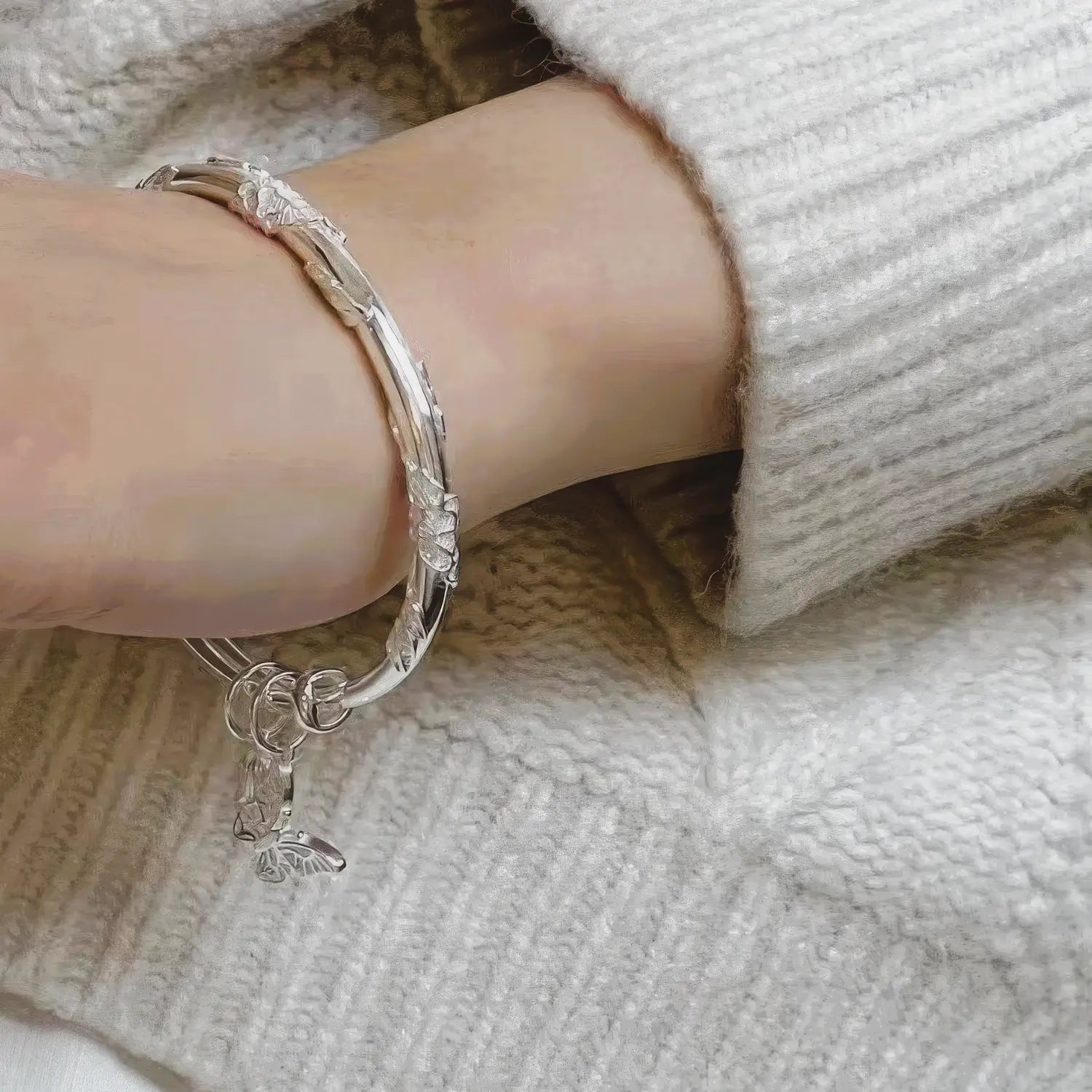 Push - pull flower hanging bell bangle worn on wrist with white sweater, highlighting style