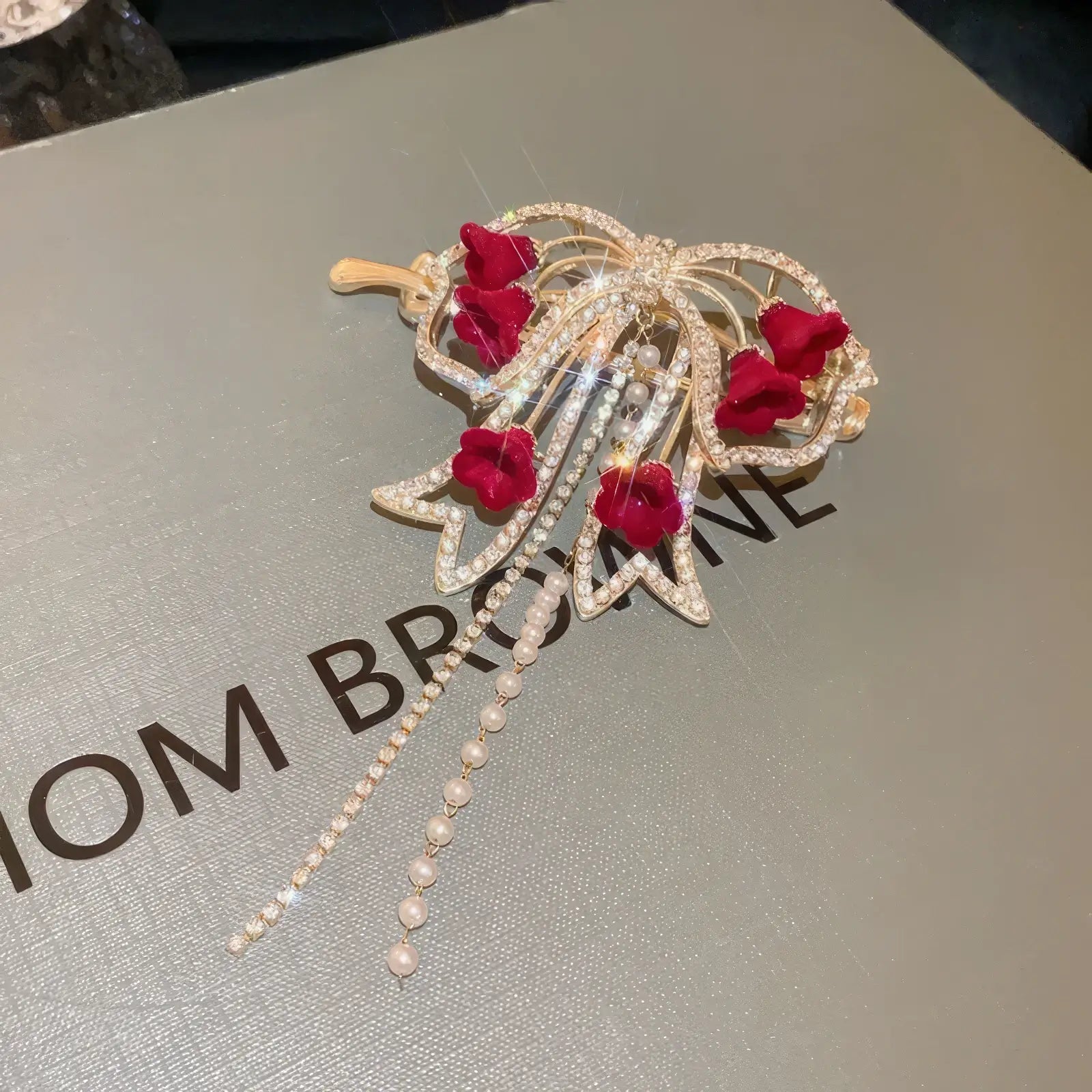 Detailed view of gold - base red flower butterfly hair clip on box