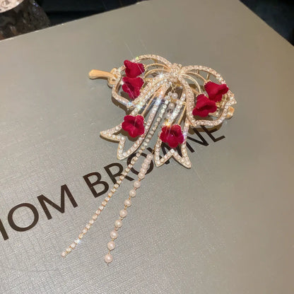 Detailed view of gold - base red flower butterfly hair clip on box