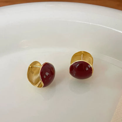 Red round ear clips placed on white plate, showing gold backing