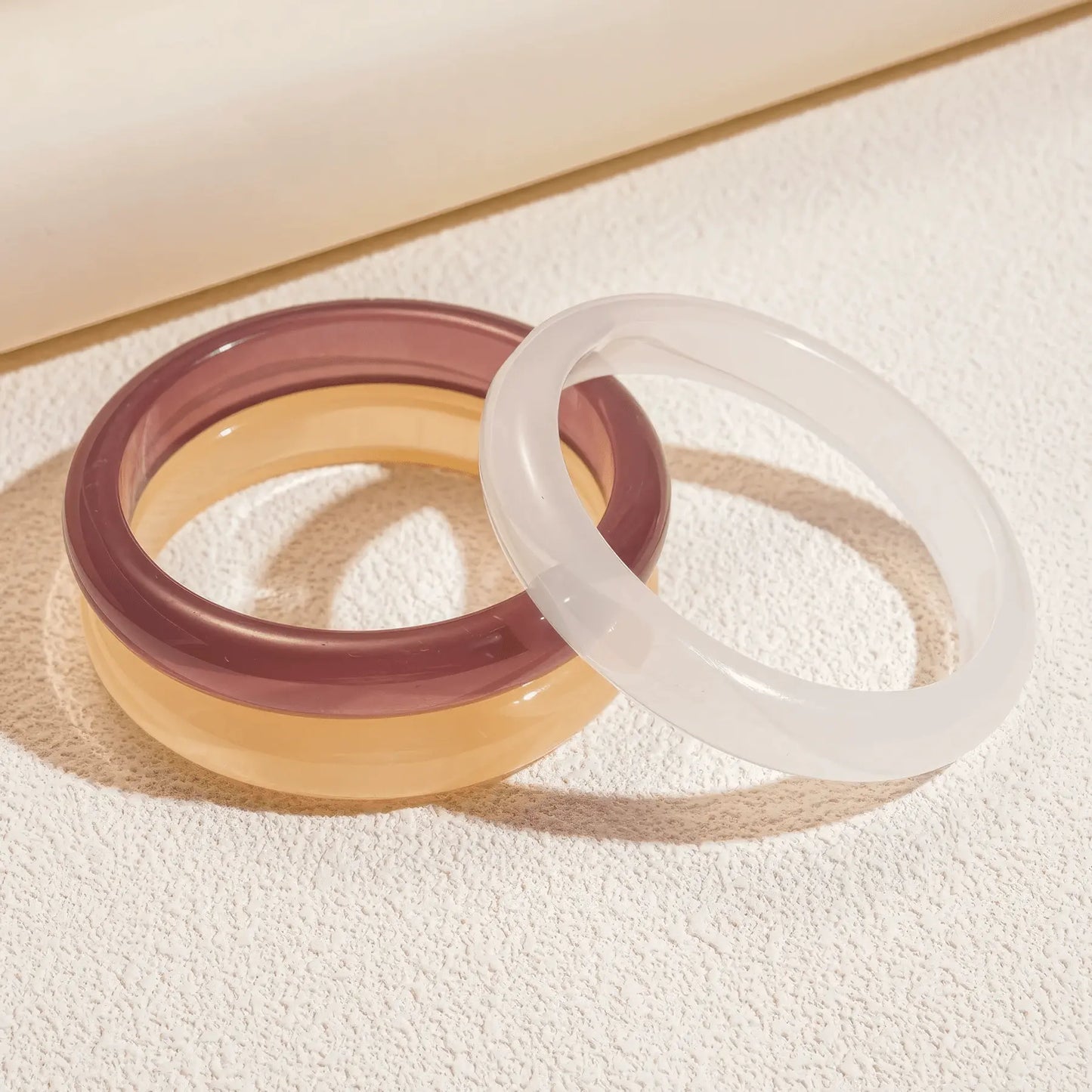 Purple and white resin geometric round bangles placed on surface, clear details