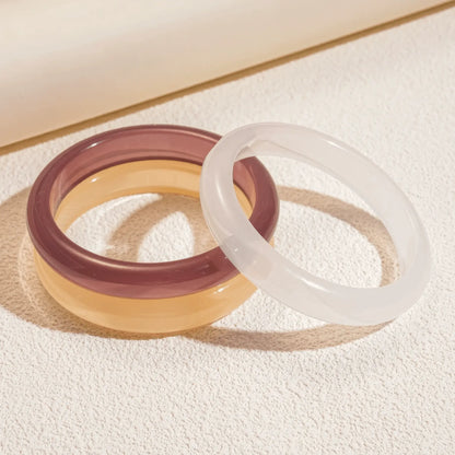 Purple and white resin geometric round bangles placed on surface, clear details