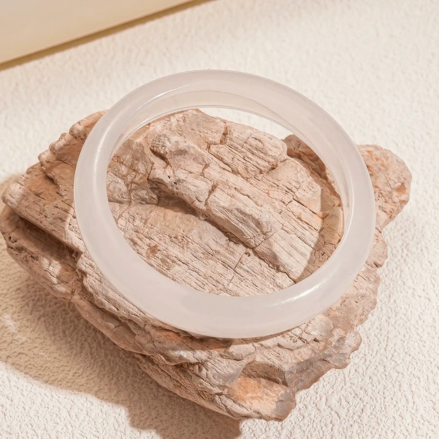 White resin geometric round bangle placed on rock, showcasing minimalist design