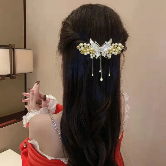 Woman wearing a rhinestone flower spring hairpin with gold accents, dressed in a red dress, back view