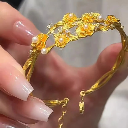 Hand holding gold rose pearl bracelet, showcasing intricate design
