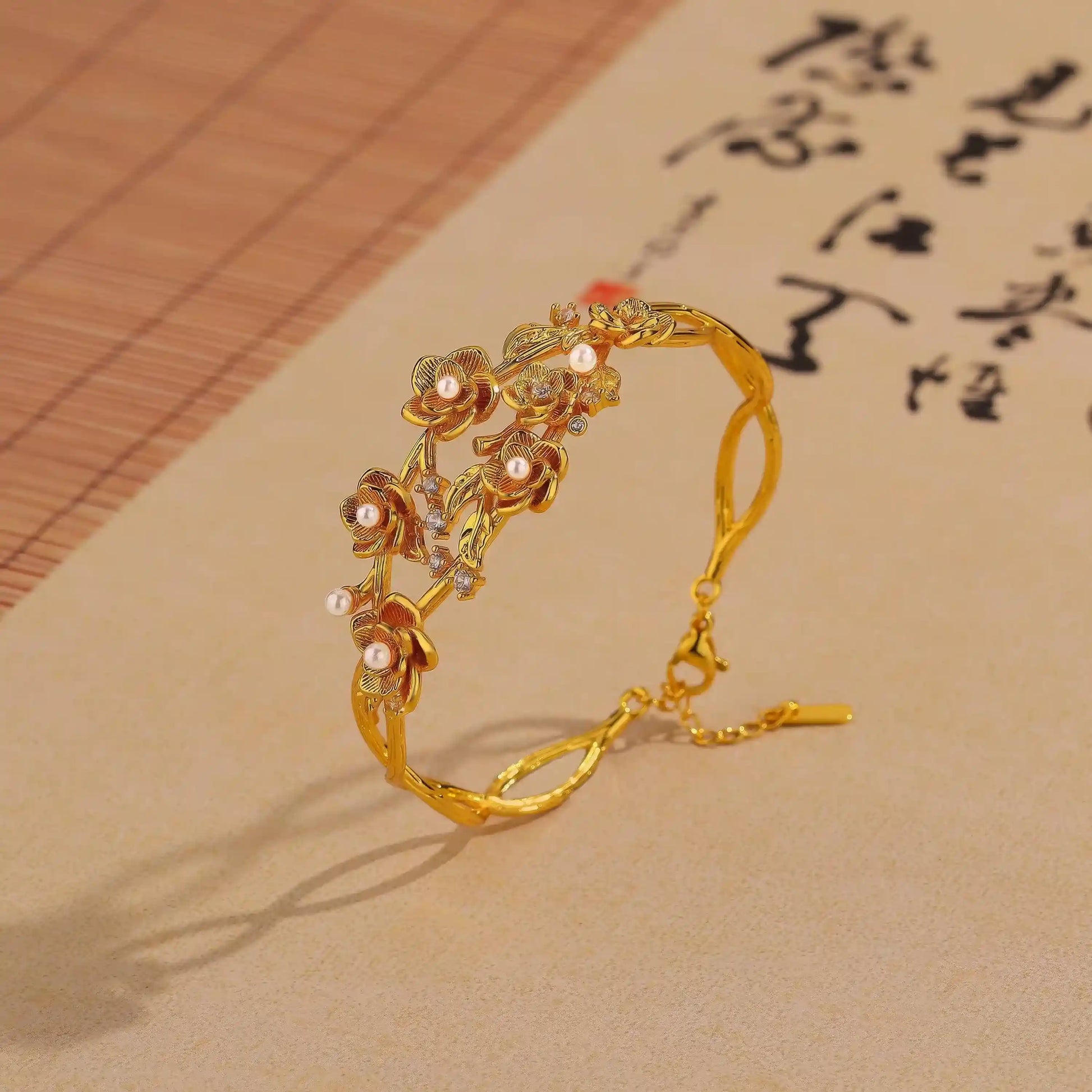 Side view of gold rose pearl bracelet placed on paper with calligraphy