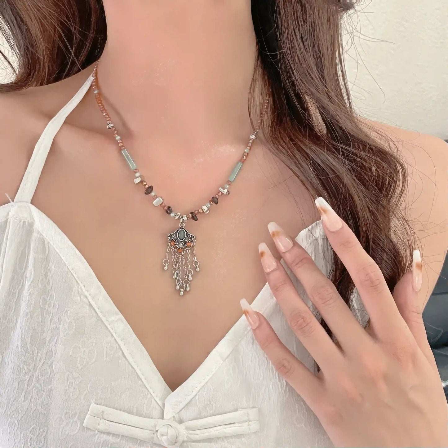 Ruyi tassel lock pendant necklace worn with a white dress, highlighting elegance