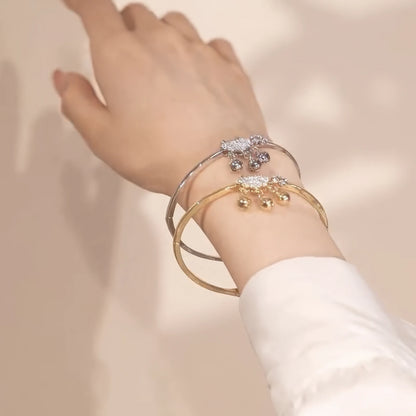 Silver and gold safety lock bracelets worn on wrist, white sleeve in background