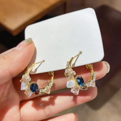 Hand holding sea blue champagne wreath earrings, showcasing details
