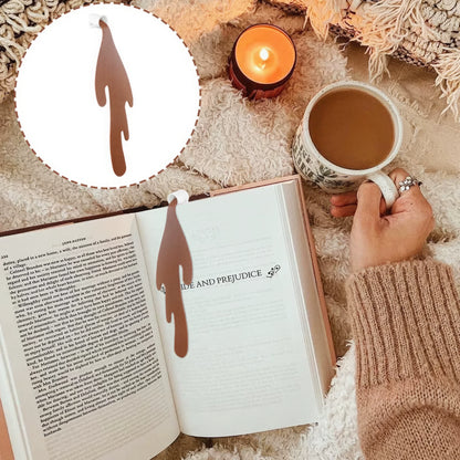 Spilled coffee - shaped bookmark in an open book, displayed in a cozy scene with candle and coffee cup, light background