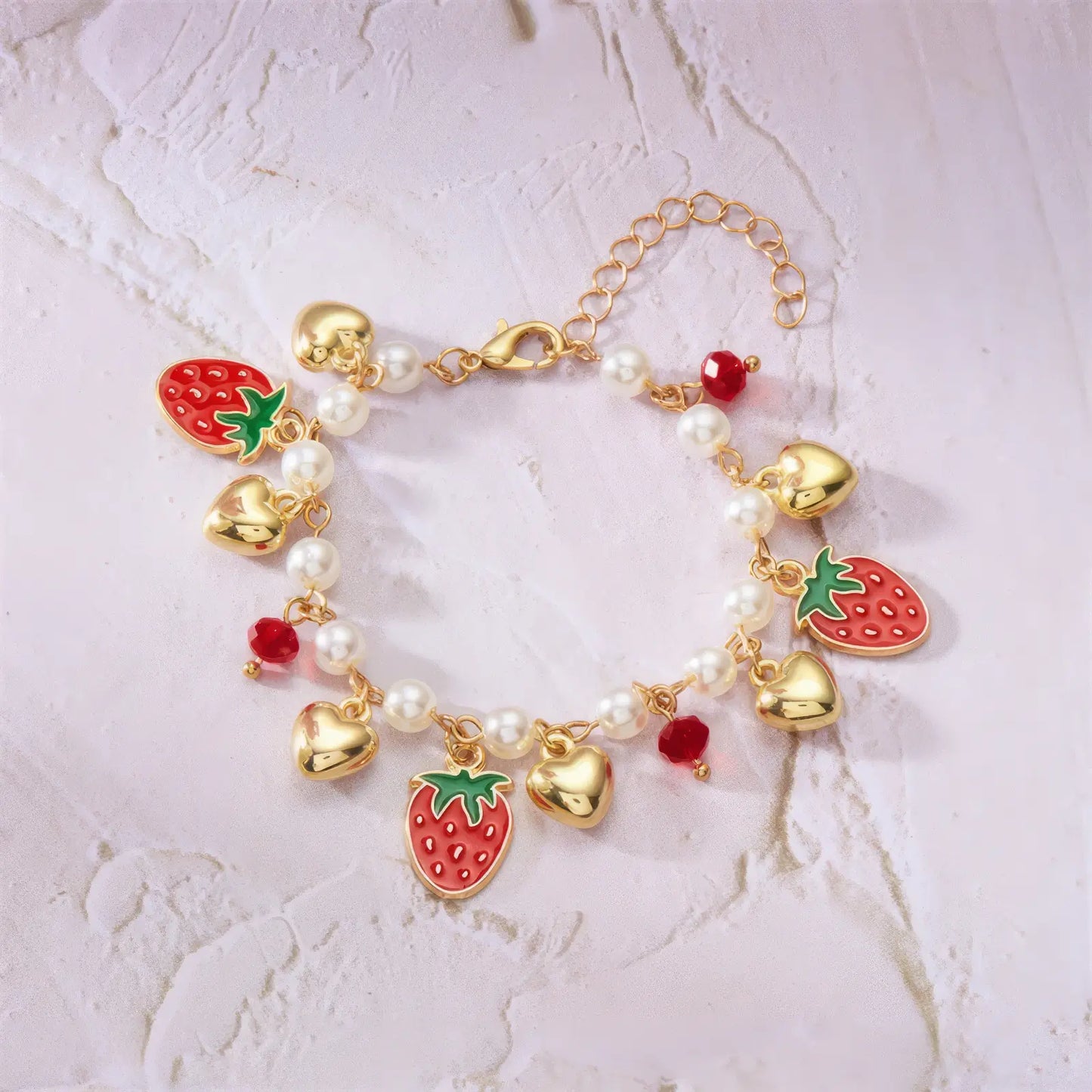 Detail of strawberry cherry heart pearl bracelet on a light surface