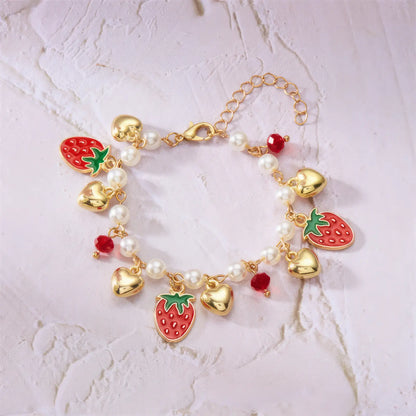 Detail of strawberry cherry heart pearl bracelet on a light surface