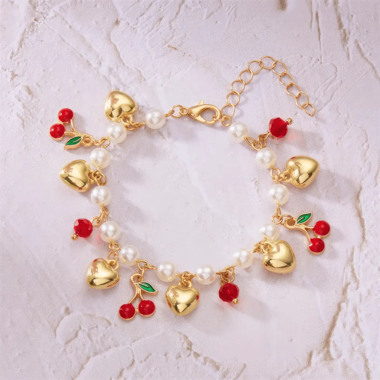 Another layout of strawberry cherry heart pearl bracelet on a light surface