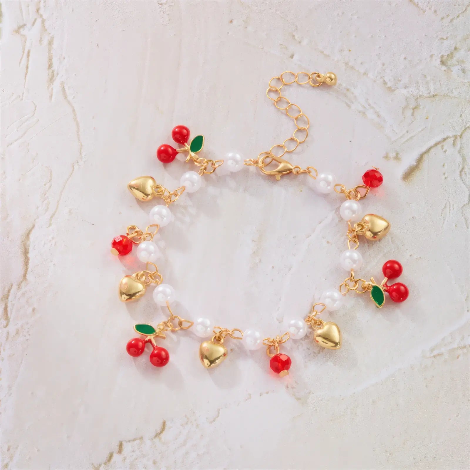 Strawberry cherry heart pearl bracelet laid out on a light surface