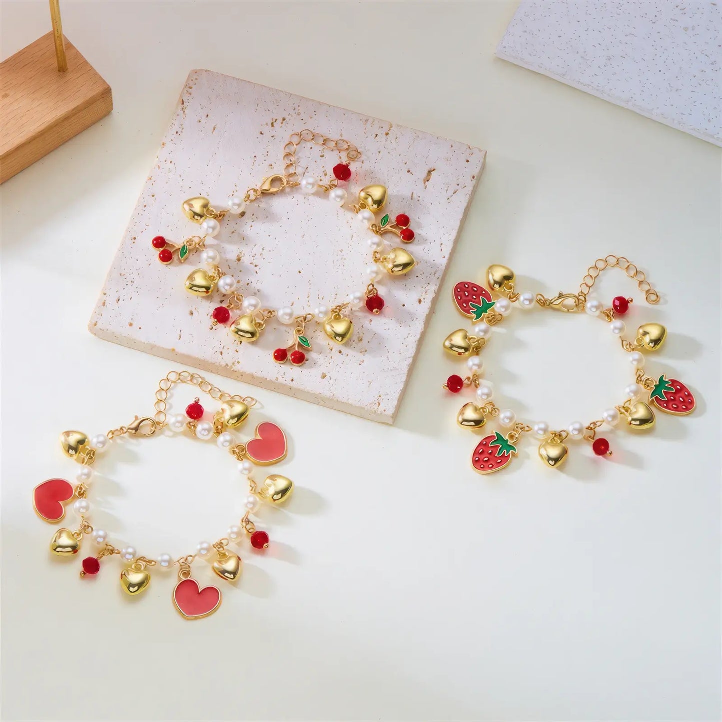 Set of strawberry cherry heart pearl bracelets on a white surface with a card