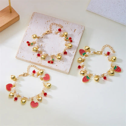 Set of strawberry cherry heart pearl bracelets on a white surface with a card
