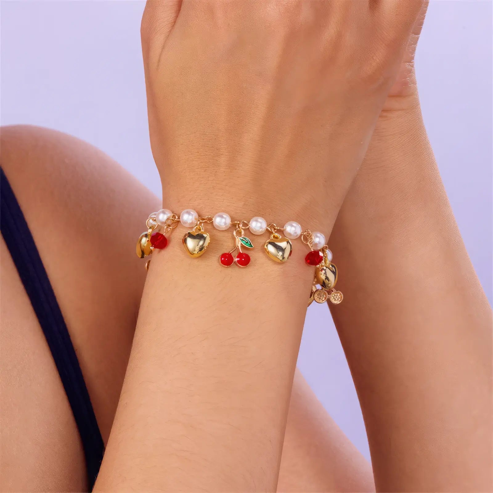 Stack of strawberry cherry heart pearl bracelets worn on wrists