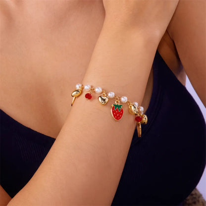 Strawberry cherry heart pearl bracelet worn on a wrist, black top background