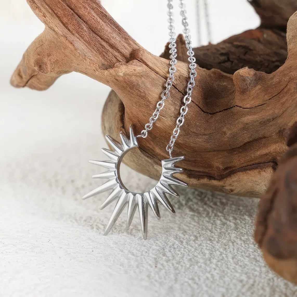 Silver sunflower necklace isolated on light background with wood
